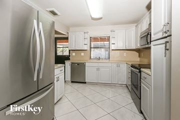 Wellington house for rent - a white kitchen with stainless steel appliances and white cabinets