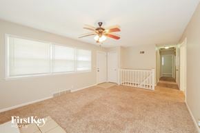 Kansas City house for rent - A spacious room with a fan and carpeted floor.