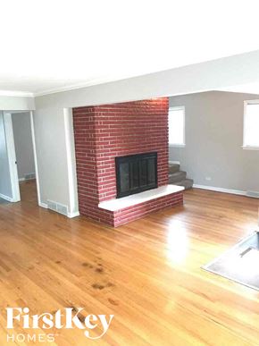 Calumet Park house for rent - an empty living room with a brick fireplace and wooden floors
