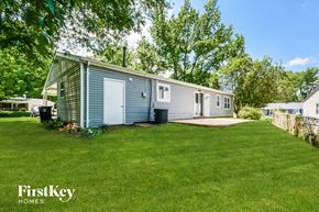 Saint Louis house for rent - a small blue and white mobile home on a grassy yard with trees