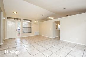 Apopka house for rent - an empty living room with a white door and tiled floor