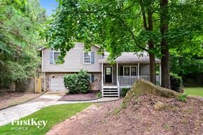 Conyers house for rent - A house with a grey roof and a white fence is surrounded by green trees.