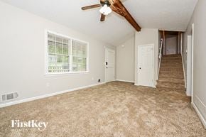 Conyers house for rent - A room with a carpeted floor and a staircase leading to another room.