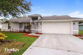 Palm Bay house for rent - a white house with a driveway and a garage door