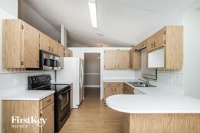 Palm Bay house for rent - a kitchen with white counters and wooden cabinets and a black stove and refrigerator
