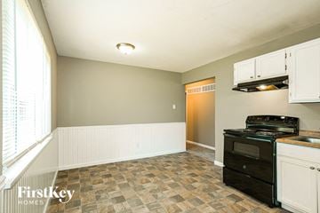 Hazelwood house for rent - A kitchen with a black stove top oven and white cabinets.
