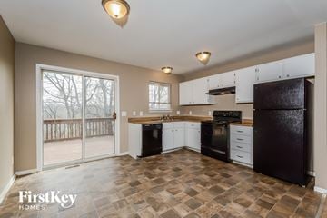Black Jack house for rent - A kitchen with a black fridge and white cabinets.