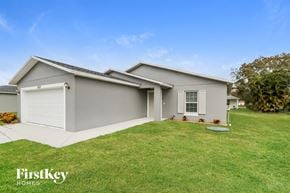 Port St. Lucie house for rent - the exterior of a gray house with a lawn and a driveway