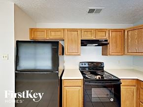 Houston house for rent - a kitchen with wood cabinets and a black refrigerator