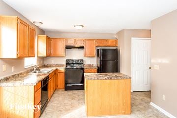 Indianapolis house for rent - a kitchen with wooden cabinets and black appliances