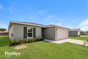 Port St. Lucie house for rent - a beige house with a lawn and a driveway