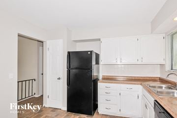 Florissant house for rent - A black fridge in a kitchen with white cabinets.