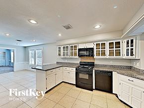 Cypress house for rent - a large kitchen with white cabinets and black appliances