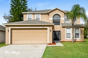 Gibsonton house for rent - a tan house with a garage door and a palm tree