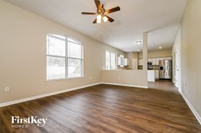 Gibsonton house for rent - an empty living room with a ceiling fan and a kitchen