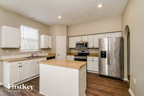 Gibsonton house for rent - a kitchen with white cabinets and a stainless steel refrigerator