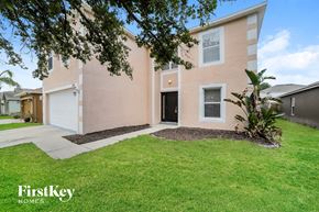 Gibsonton house for rent - a pink house with a green lawn and a white garage door