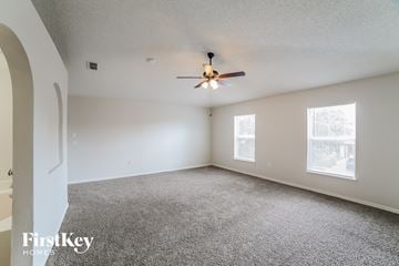 Gibsonton house for rent - a living room with carpet and a ceiling fan