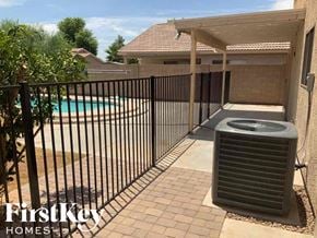 El Mirage house for rent - A black gate surrounds a pool and leads to a patio with a black air conditioning unit.