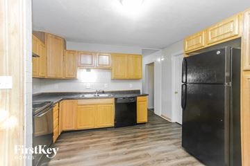 Greenwood house for rent - A kitchen with wooden cabinets and a black fridge.