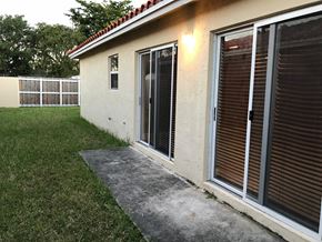 Homestead house for rent - a side view of a house with sliding glass doors and a concrete walkway outside