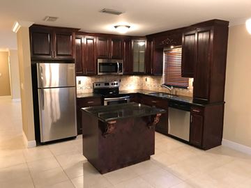Homestead house for rent - a kitchen with stainless steel appliances and dark wood cabinets