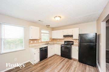 Stone Mountain house for rent - A kitchen with black appliances and wooden floors.