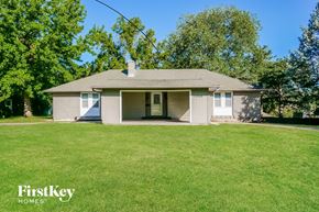 Independence house for rent - a small tan house with a green lawn and trees