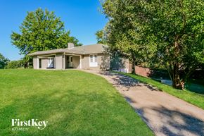 Independence house for rent - a white house with a driveway and a lawn and trees