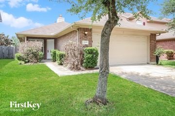 Houston house for rent - a home with a garage and a tree in the front yard