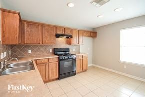 Houston house for rent - a kitchen with wooden cabinets and a stove and a sink