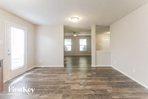 Fishers house for rent - A spacious room with a wooden floor and white walls, with a door on the right side.