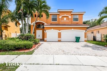 Miramar house for rent - a orange house with white garage doors and palm trees
