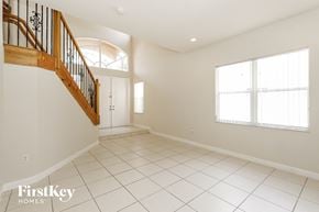 Miramar house for rent - the living room and entryway of a house with white tiled floors and stairs