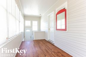 Waukegan house for rent - a room with wood floors and white walls and a white door with a red mirror