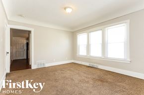 Waukegan house for rent - an empty living room with a carpeted floor and three windows