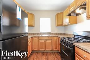 Waukegan house for rent - a kitchen with wooden cabinets and a stove and a refrigerator