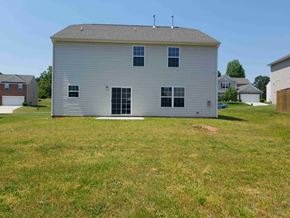 Greensboro house for rent - A large grey barn with a grey roof and a grey door stands in a grassy field.