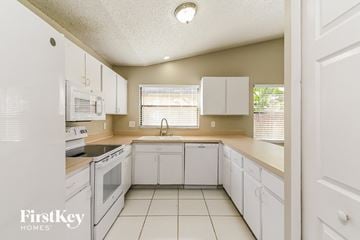 Valrico house for rent - a kitchen with white cabinets and white appliances and white tiled floors