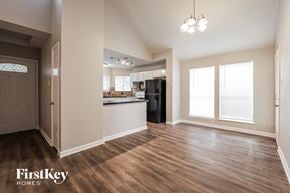 Houston house for rent - A spacious room with wooden floors and a kitchen in the background.