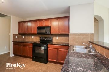 Royse City house for rent - a kitchen with granite counter tops and wooden cabinets