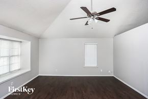 Allen house for rent - A room with a ceiling fan and wooden floors.