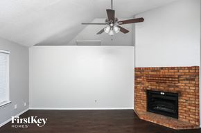 Allen house for rent - A room with a brick fireplace and a ceiling fan.