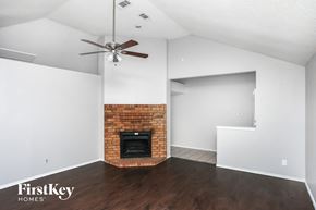 Allen house for rent - A room with a brick fireplace and a ceiling fan.