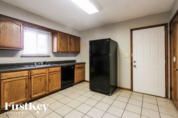 Indianapolis house for rent - A kitchen with wooden cabinets and a black fridge.