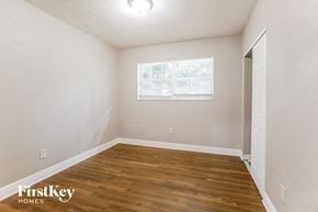 Miami house for rent - a bedroom with white walls and wood flooring and a window