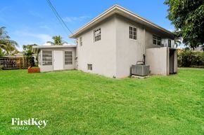 Miami house for rent - a small white house with a grass yard and a garage
