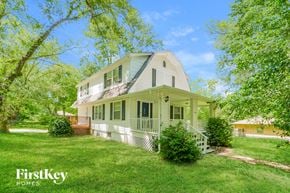 Grandview house for rent - A white house with a porch and a tree in front of it.