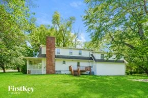 Grandview house for rent - A white house with a brick chimney is surrounded by trees.