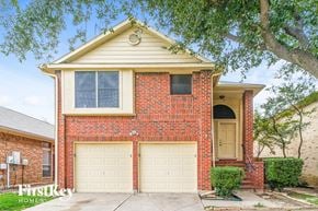 Lewisville house for rent - A two-car garage is attached to a red brick house.